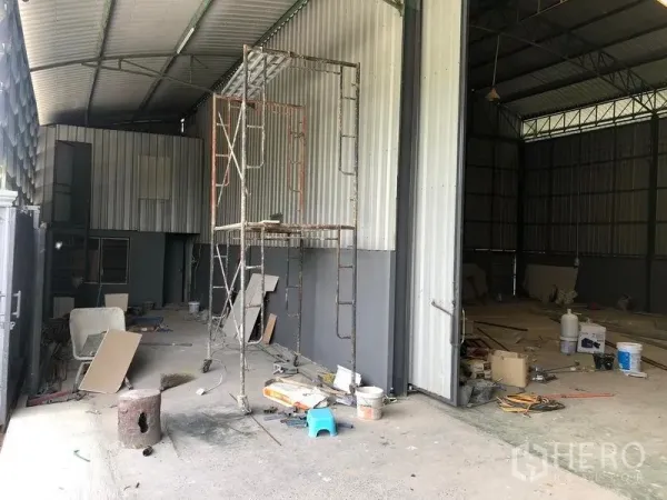 货栈 出租在Lam Luk Ka, Pathum Thani - 仓库侧边有顶装卸区，金属围护与大型滑门，现场脚手架。
