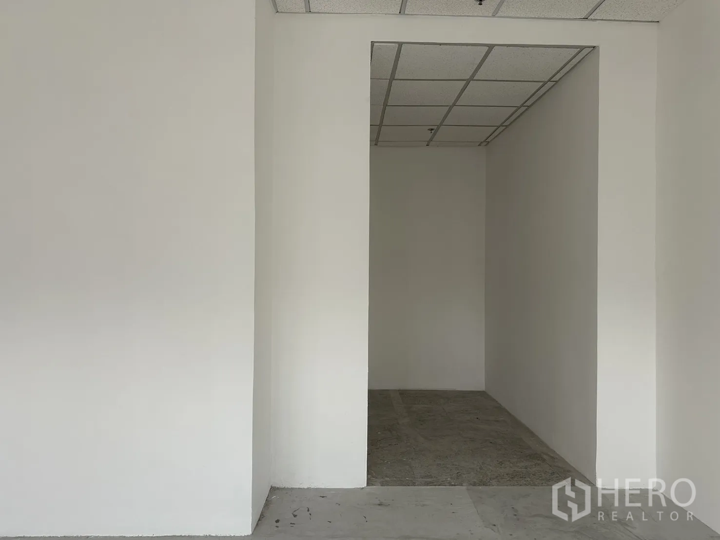 Office Space for rent in Khlong Toei, Bangkok - Small internal room with white walls, grid drop ceiling, and unfinished concrete floor.