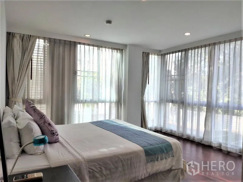 Condominium for rent in Bang Rak, Bangkok - Second bedroom with floor-to-ceiling windows and soft drapes.