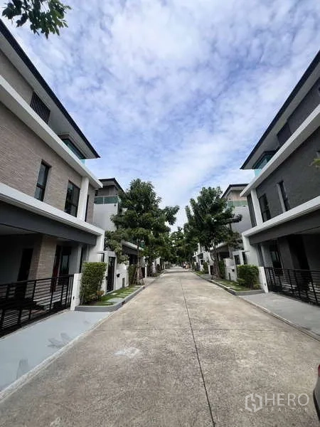 Detached House for rent in Wang Thonglang, Bangkok - Tree-lined private road inside a gated housing community with modern homes on both sides.