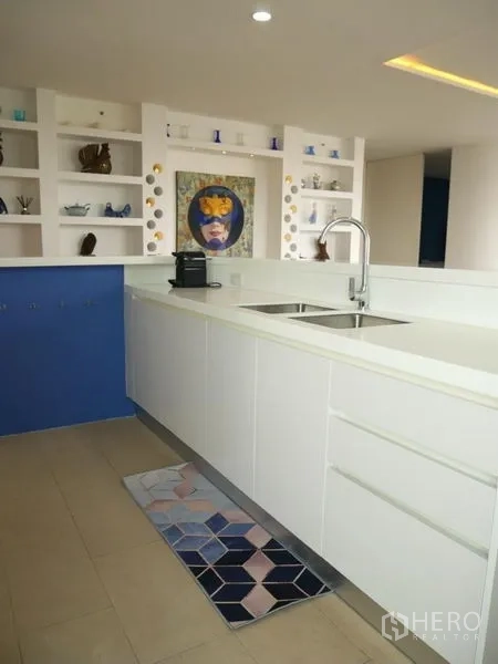 Condominium for rent in Khlong Toei, Bangkok - White cabinetry kitchen with double sink and display shelving.