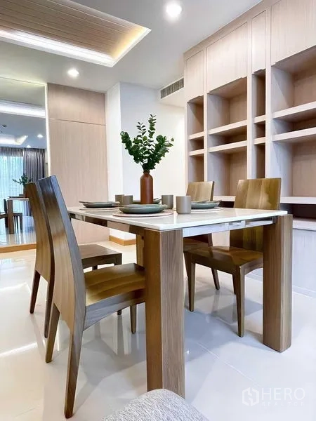 Condominium for rent - Dining area set for four with a wooden table and built-in shelves.