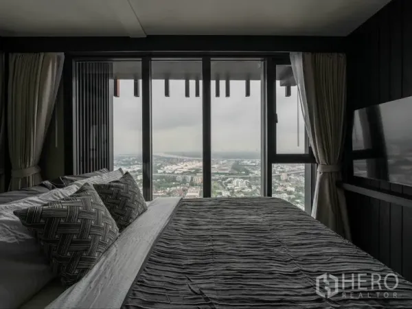 公寓 出租或出售在Phra Khanong, Bangkok - 卧室配大床，落地窗外是曼谷全景天际线。