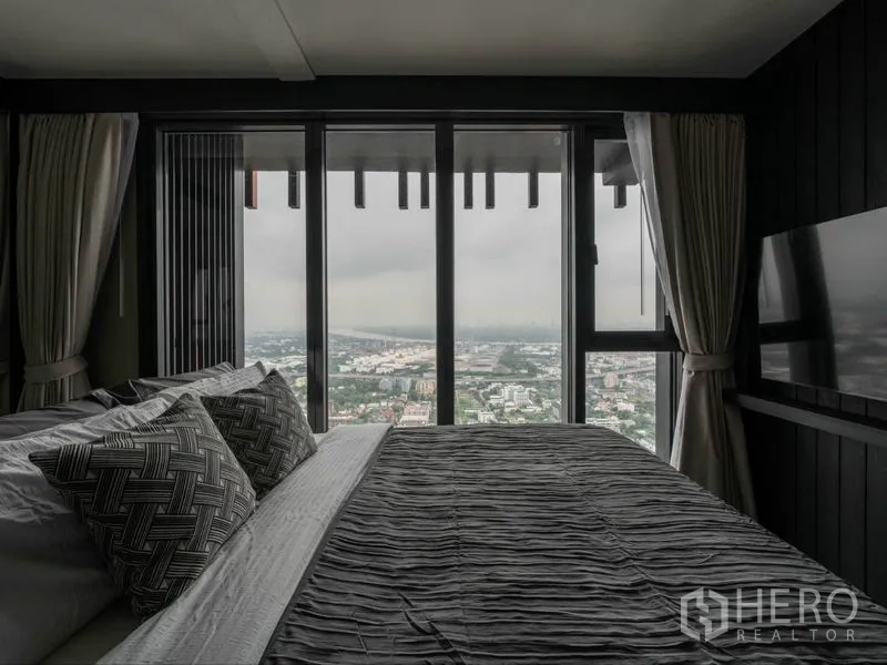 公寓 出租或出售在Phra Khanong, Bangkok - 卧室配大床，落地窗外是曼谷全景天际线。