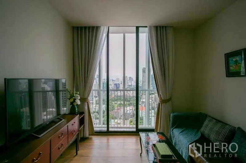 Condominium for sale in Khlong Toei, Bangkok - Panoramic Bangkok skyline seen through floor-to-ceiling sliding doors and balcony rail.