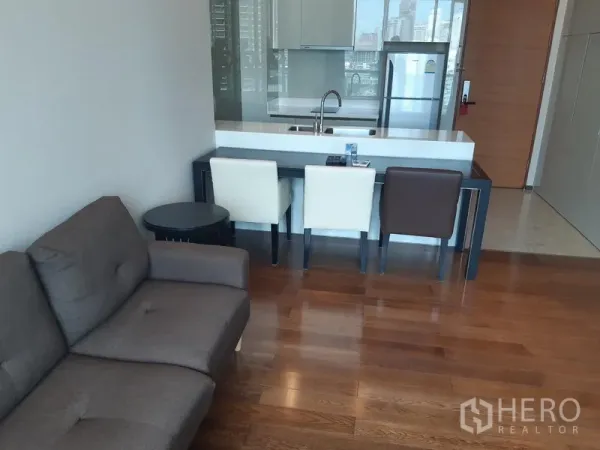Condominium for rent in Khlong Toei, Bangkok - Open-plan kitchen with breakfast bar, dining set and hardwood floors.