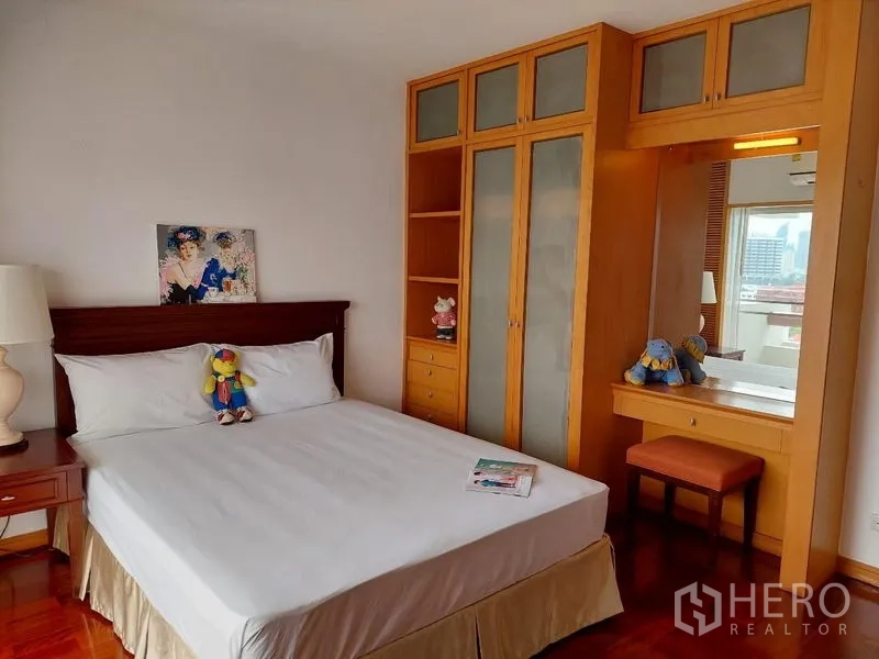 Apartment for rent - Sathon Bangkok apartment bedroom with built-in wooden wardrobe, dressing table and hardwood floor.