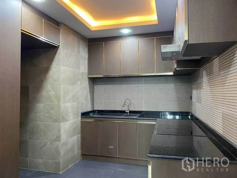 Condominium for rent in Khlong Toei, Bangkok - L-shaped kitchen with granite countertops, tiled splashback and under-cabinet lighting.