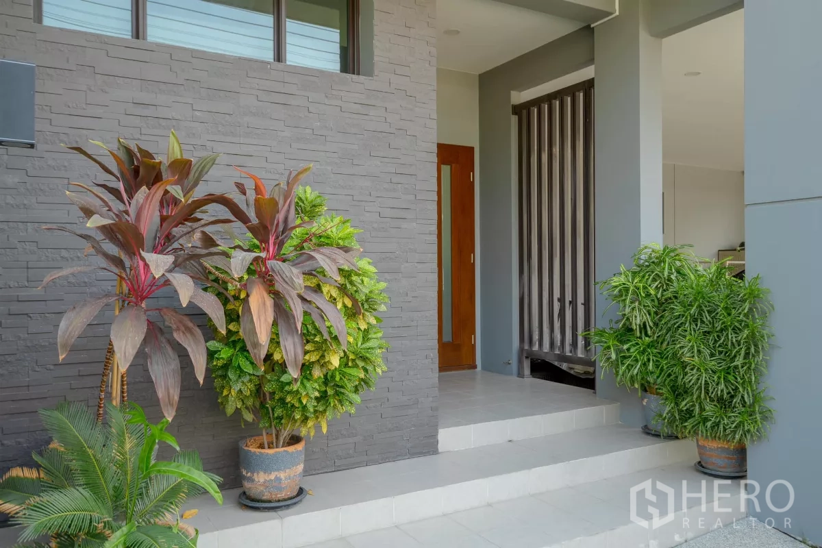Detached House for sale in Saphan Sung, Bangkok - Covered entrance with potted plants and a textured stone feature wall.