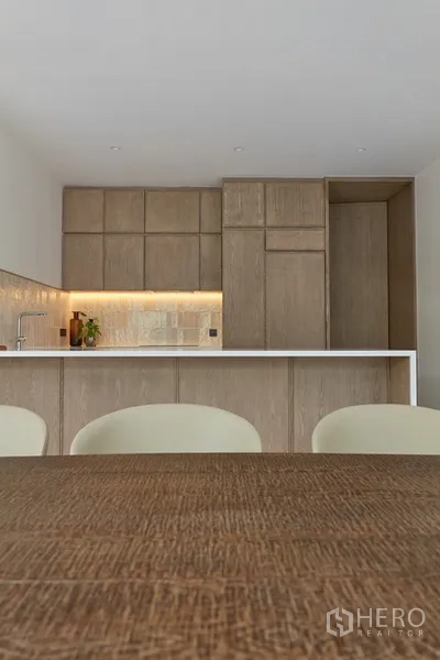 Detached House for rent in Watthana, Bangkok - Light wood kitchen with an island, built-in cabinets and warm under-cabinet lighting.