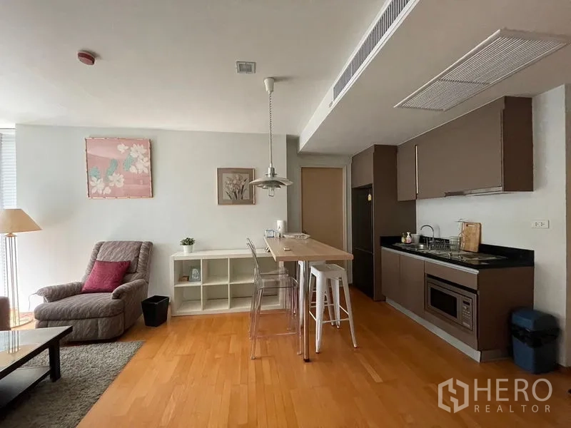 Condominium for sale in Khlong Toei, Bangkok - Kitchenette with built-in cabinets, breakfast island and adjoining living area.