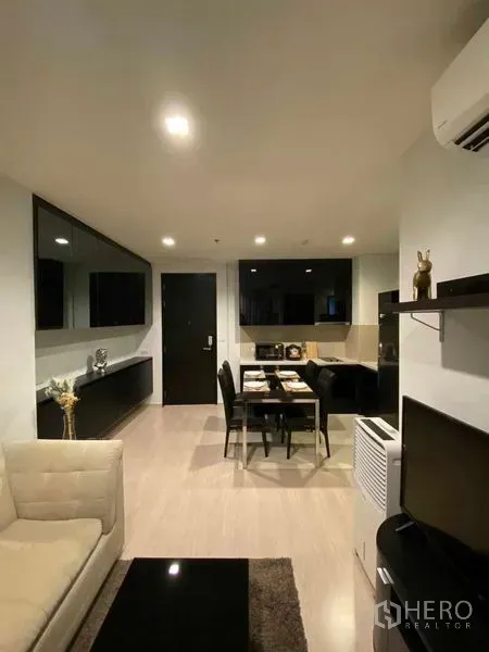 Condominium for rent in Khlong Toei, Bangkok - Open-plan living and dining area with black cabinetry, four-seat dining table and recessed lighting.