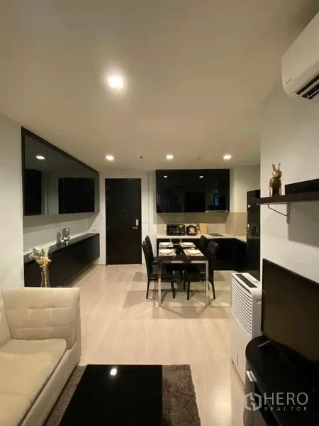 Condominium for rent in Khlong Toei, Bangkok - Open-plan living and dining area with black cabinetry, four-seat dining table and recessed lighting.