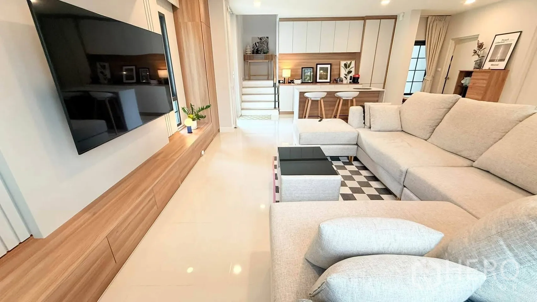 บ้านเดี่ยว for rent in Bang Phli, Samut Prakan - ห้องนั่งเล่นมีโซฟาเข้ามุมขนาดใหญ่ ทีวีติดผนัง และโต๊ะกลางลายตาราง