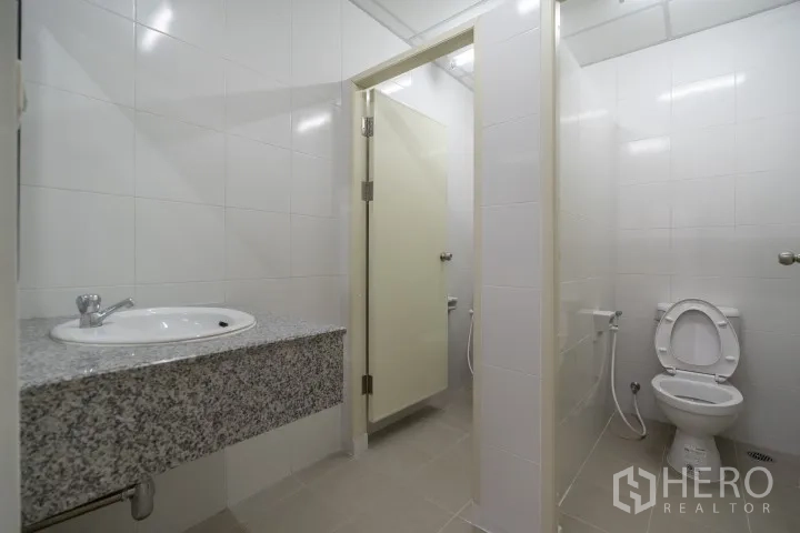 Factory for rent in Khlong Luang, Pathum Thani - Clean tiled restroom with sink counter, toilet, and separate stall.
