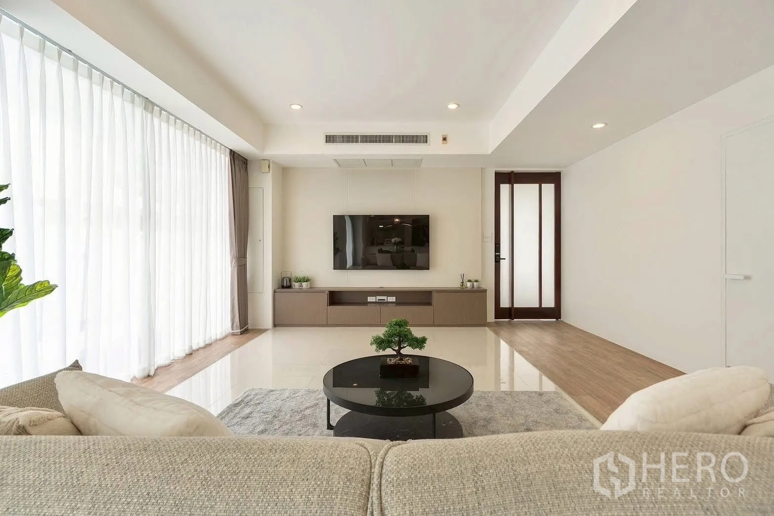 Detached House for rent in Saphan Sung, Bangkok - Living room with large TV wall unit and sheer curtain windows.