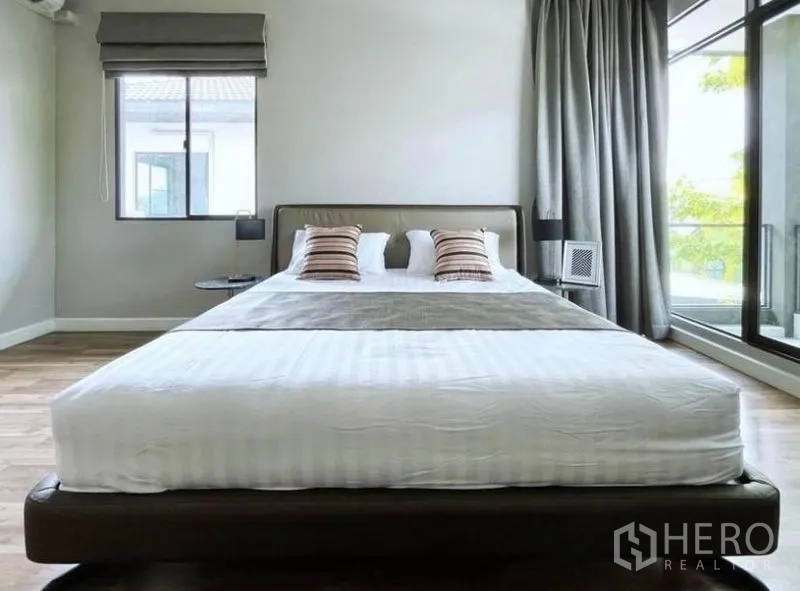 Detached House for rent in Prawet, Bangkok - Front view of the master bedroom with wood floors, large windows and balcony access.
