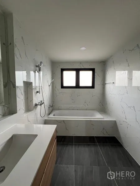 Detached House for rent or sale in Bang Phli, Samut Prakan - Bathroom with bathtub, marble-effect walls, window and handheld shower.