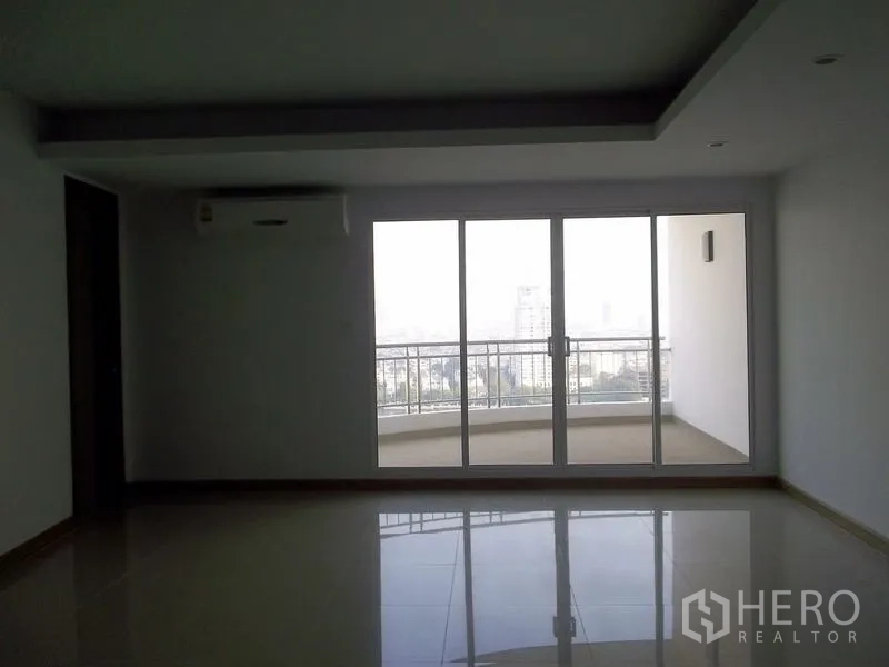 公寓 出租在Bangkok - 起居区面向玻璃门，通往弧形阳台，可观天际线景观。