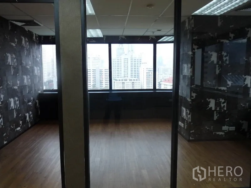 Office Space for rent in Watthana, Bangkok - Two glass-partitioned rooms with patterned wallpaper and skyline views beyond.