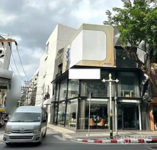 Shophouse for rent in Watthana, Bangkok - Corner shophouse with double-height glass façade and a prominent billboard in the Phrom Phong area of Watthana, Bangkok.