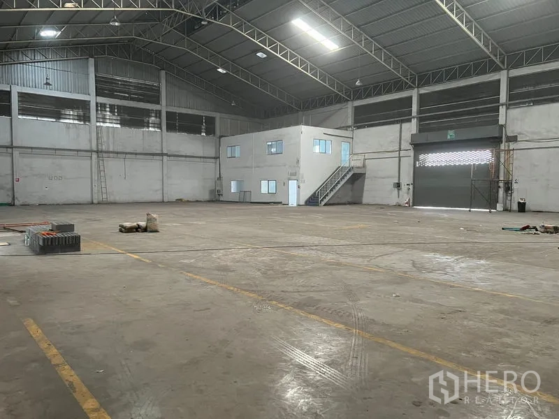 货栈 出租在Bang Sao Thong, Samut Prakan - 宽阔仓库内部，卷帘装卸门与办公室盒体。