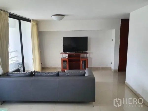 公寓 出售在Watthana, Bangkok - 明亮客厅，灰色沙发与电视柜，落地玻璃门通往阳台。