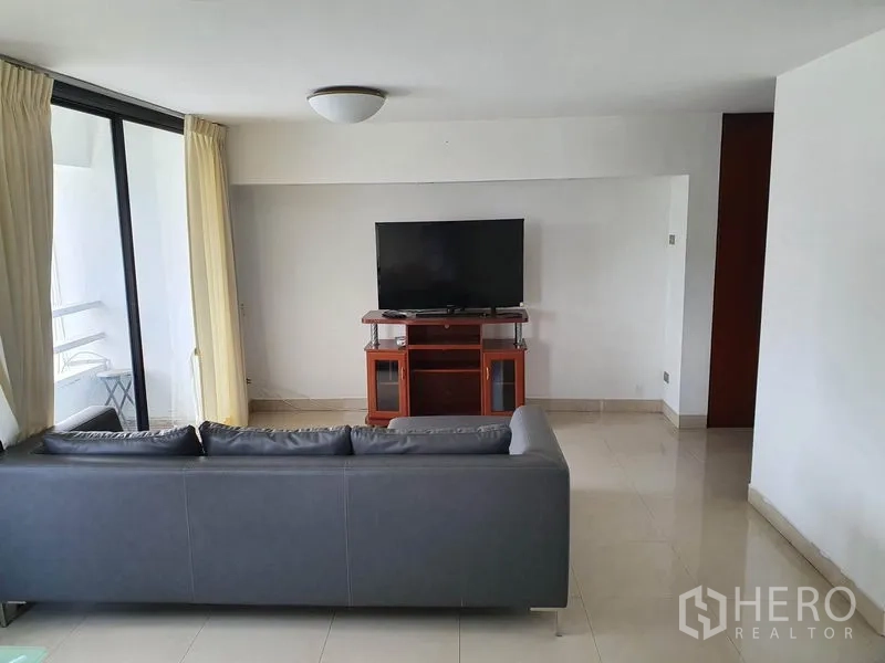 公寓 出售在Watthana, Bangkok - 明亮客厅，灰色沙发与电视柜，落地玻璃门通往阳台。