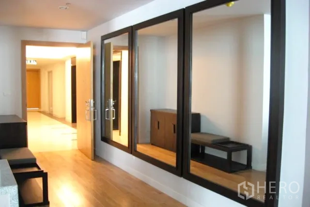 Condominium for sale in Khlong Toei, Bangkok - Entry hallway with large wall mirrors, wooden flooring, and double doors leading toward the living area.