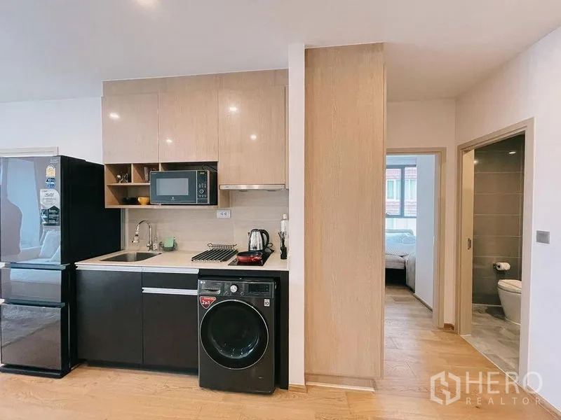 Condominium for rent in Ratchathewi, Bangkok - Modern kitchenette with microwave, cooktop, fridge and in‑unit washer.