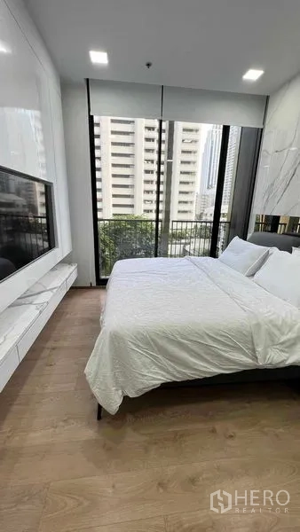 Condominium for rent in Watthana, Bangkok - Bedroom with floor-to-ceiling windows, balcony view and wall-mounted TV.