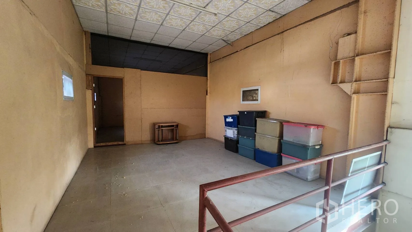 Warehouse for rent in Nonthaburi - Mezzanine storage area with railing and stacked plastic bins.