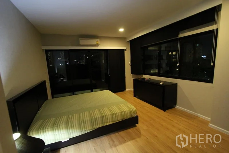 คอนโด ให้เช่าในPathum Wan, Bangkok - ห้องนอนที่สอง มีหน้าต่างบานใหญ่ เห็นวิวเมืองยามค่ำ และม่านกันแสง