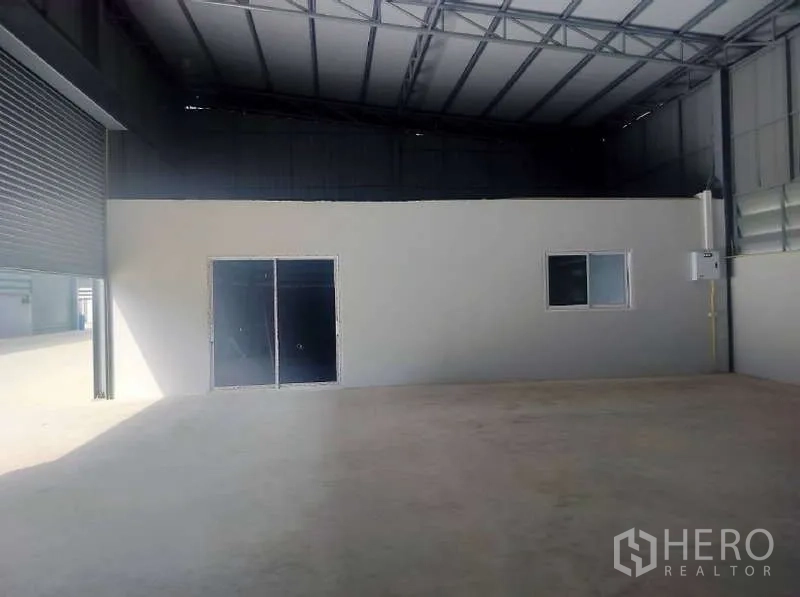 货栈 出租在Pathum Thani - 卷闸大门入口，仓库内设有带窗的小型办公间。
