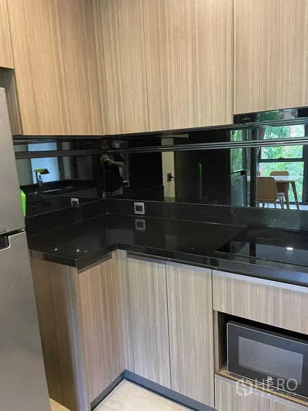 Condominium for rent in Watthana, Bangkok - Compact separate kitchen with wood cabinetry and black stone countertops.