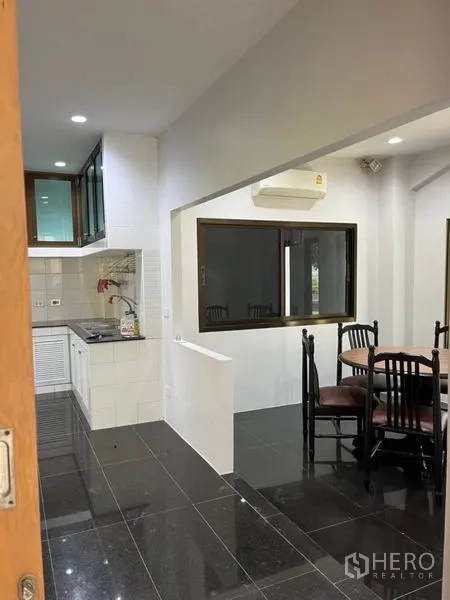 Detached House for rent in Samut Prakan - Dining area beside the kitchen with four chairs and split‑type air conditioner.