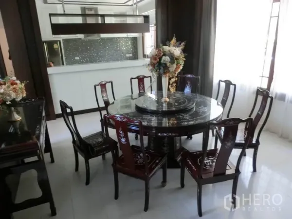 Detached House for rent in Bang Phli, Samut Prakan - Formal dining area with an elegant round table and eight chairs next to a bright open kitchen.
