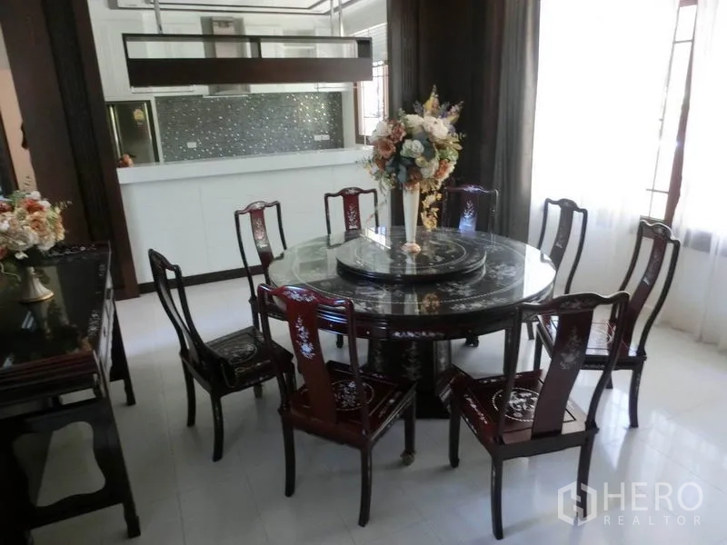 Detached House for rent in Bang Phli, Samut Prakan - Formal dining area with an elegant round table and eight chairs next to a bright open kitchen.