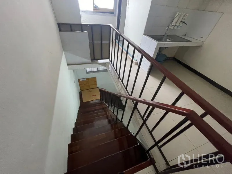 Shophouse for rent in Phra Khanong, Bangkok - Stairwell view down to a landing with a utility sink and window.