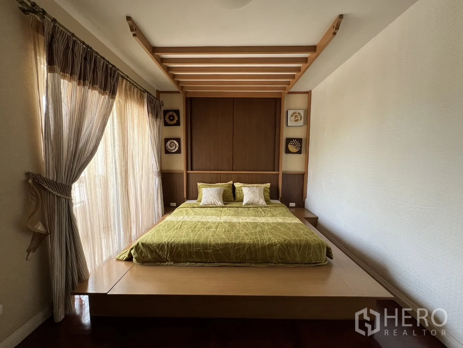 บ้าน ให้เช่าในLat Krabang, Bangkok - ห้องนอนที่สอง เตียงยกพื้น หัวเตียงไม้ตกแต่ง และผ้าม่านโปร่ง
