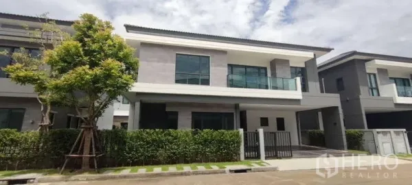 独立式住宅 出租在Bang Phli, Samut Prakan - 现代两层独栋别墅外观，带阳台、车棚与绿篱围合。