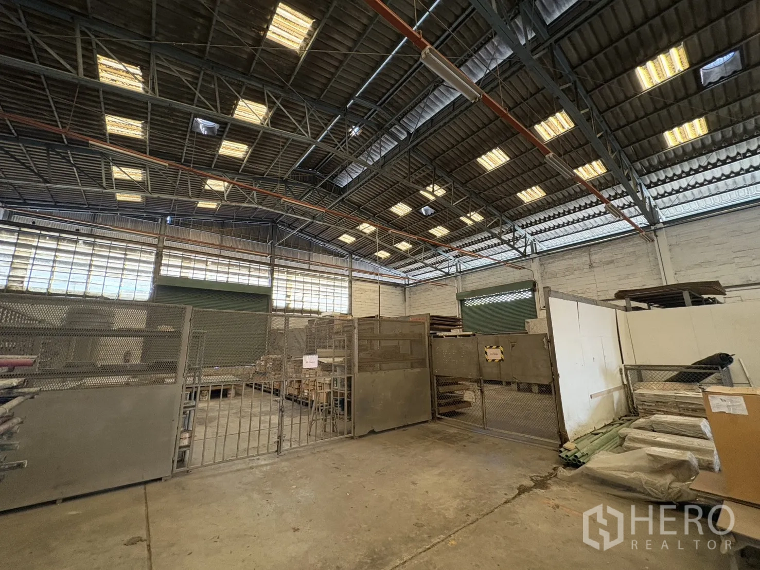 工厂 出售在Khlong Toei, Bangkok - 网格围栏仓储区，旁有绿色卷门