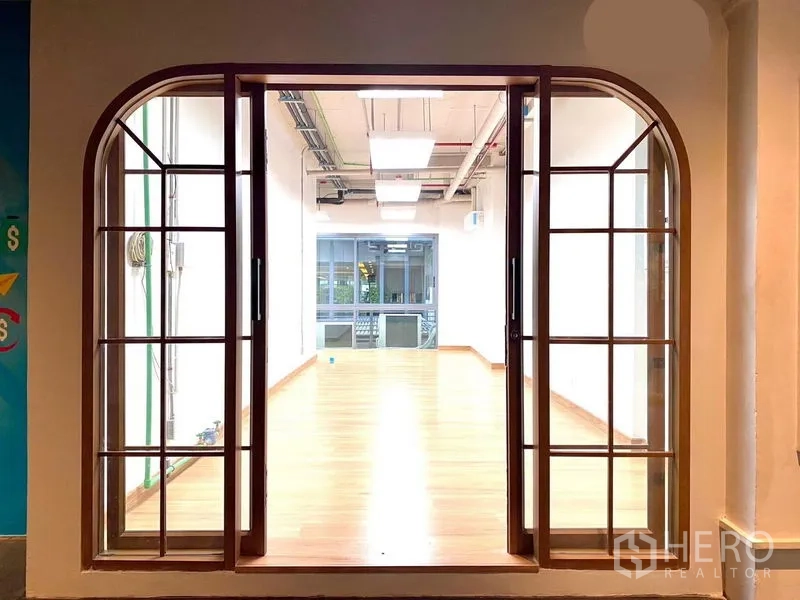 Office Space for rent in Khlong Toei, Bangkok - Arched glass sliding doors opening to a bright wood‑floored office.