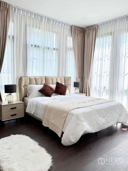 Detached House for rent or sale in Bang Phli, Samut Prakan - Corner bedroom with tufted headboard, white linens and two-tone curtains across multiple windows.