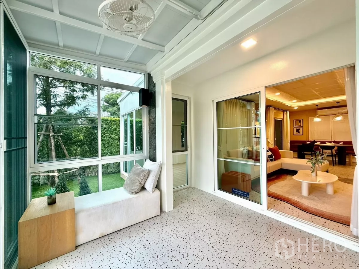 Detached House for rent in Bang Phli, Samut Prakan - Sunroom seating bench by floor-to-ceiling windows facing greenery.
