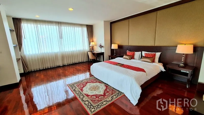 Apartment for rent in Watthana, Bangkok - King bedroom with desk, long curtain wall and warm wooden flooring.