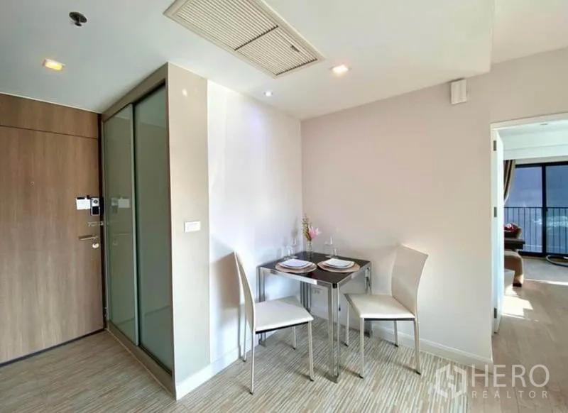 Condominium for rent in Khlong Toei, Bangkok - Entry corner with a two-seat dining table next to a sliding door and bedroom access.