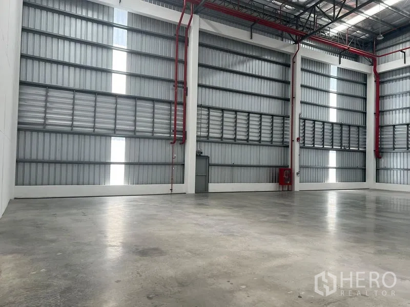 工厂 出租在Bang Pakong, Chachoengsao - 宽敞仓储区，金属夹芯墙面，天窗采光与红色消防管线清晰可见。