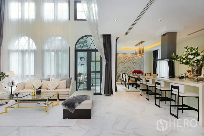独立式住宅 出租或出售在Watthana, Bangkok - 挑高拱窗下的开放式客厅、餐厅与中岛厨房。