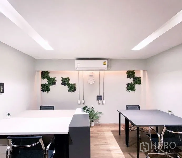 Office Space for rent in Bang Rak, Bangkok - Compact workspace with two desks, wall-mounted AC, a clock, and greenery accents.